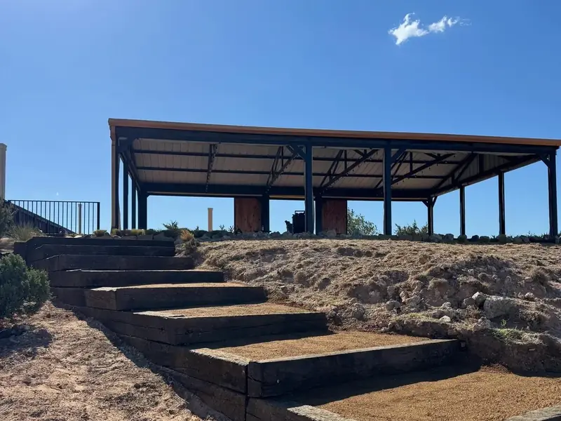 Railroad-tie steps and a graded slope leading up to a metal pavilion